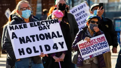 Getty Images Protesters hold a sign reading 'make election day a national holiday'