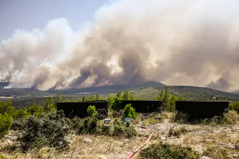 AFP Water tanks for firefighting helicopters are pictured after wildfires broke out in the area of Magoula, southwest of Athens, Greece