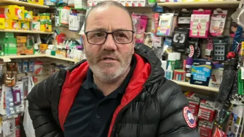 Easington Colliery shopkeeper Darren Johnson behind the counter in his shop