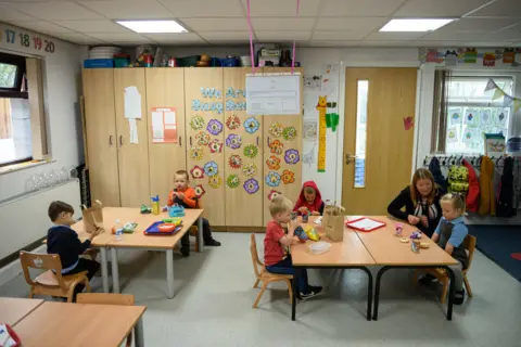 Getty Images Pre-school teacher supervises a group of young children