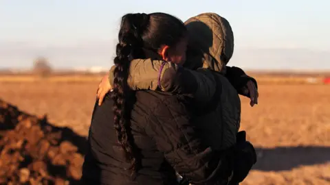 Getty Images A woman and child hold each other near the US/Mexico border