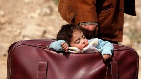 Reuters A child sleeps in a bag in the village of Beit Sawa, Eastern Ghouta (15 March 2018)