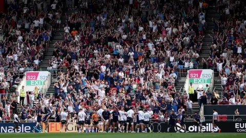 Ryan Hiscott/Getty Images Bristol Bears players celebrate a try against Saracens with fans celebrating in the stands behind them