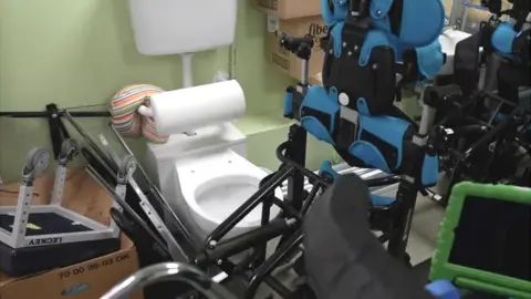 BBC/Dan Nelson Wheelchairs and equipment surround a toilet area