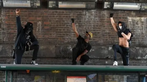 AFP Three men demonstrate on top of a bus stop