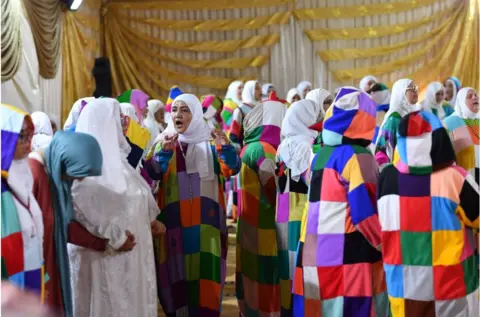 Getty Images Women gathering in hijabs wearing colourful clothing in a quilt style.