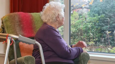 Getty Images An old woman on her own looking out the window