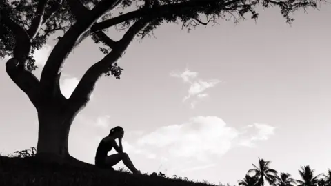 Getty Images A silhouette of a woman sitting under a tree