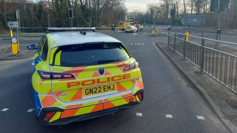 Kent Police The back of a sign-written police car blocking a road with cordons in place in the distance