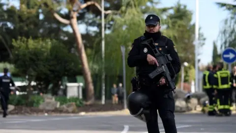 Getty Images A Spanish policeman helps to secure the area after a letter bomb explosion at the Ukrainian embassy in Madrid on Wednesday