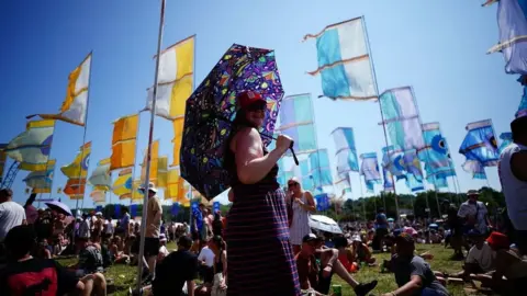 Festival-goer holding an umbrella with flags in the background