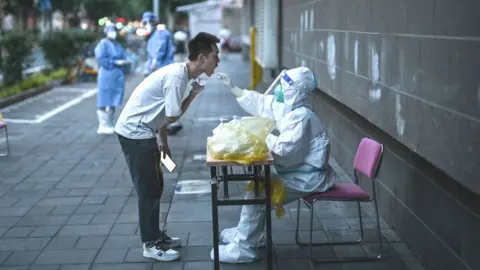 Getty Images A health worker takes a swab sample from a man to test for the Covid-19 coronavirus in the Jing'an district of Shanghai on July 5, 2022.