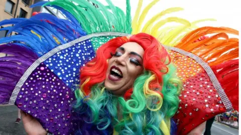 AFP/Getty Images A marcher wears an oversized feather collar featuring the colours of the rainbow flag