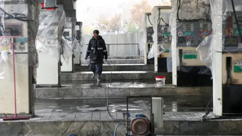 Reuters A man walks near the remains of petrol pump stands, during protests against increased fuel prices, in Tehran, Iran, 20 November, 2019.