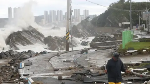 YONHAP NEWS AGENCY A man walks on a road along the coast damaged by Typhoon Hinnamnor in Ulsan