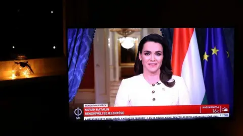 Reuters A screen shows the Hungarian President Katalin Novak as she announces her resignation