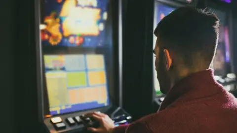 Getty Images Man gambling on fruit machine