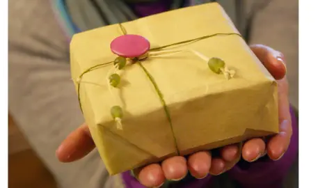 Woman holds present forward that has been hand wrapped