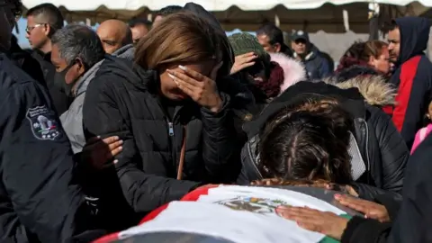 AFP People mourn over the coffin of one of the guards killed in Sunday's prison attack in Ciudad Juárez, Mexico