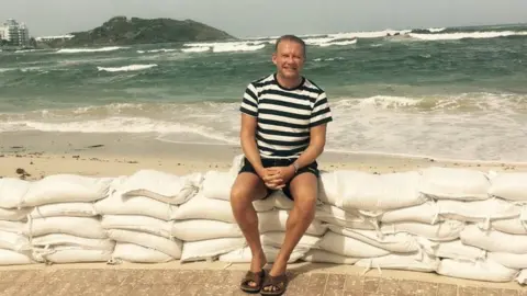 Twitter/Alex Woolfall Alex Woolfall sitting on sandbags