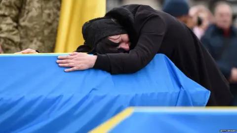 Getty Images Woman cries on coffin in Ukraine