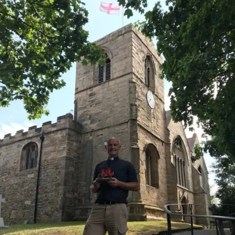 Rev Gary Schofield, Vicar of Wales, outside his church