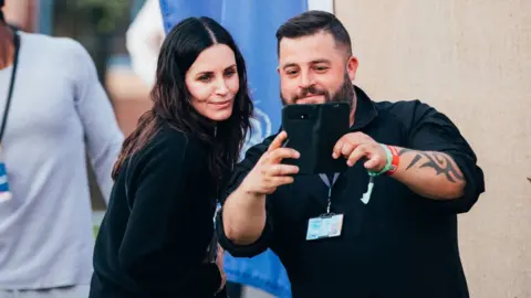 PA Media Courtney Cox with a fan