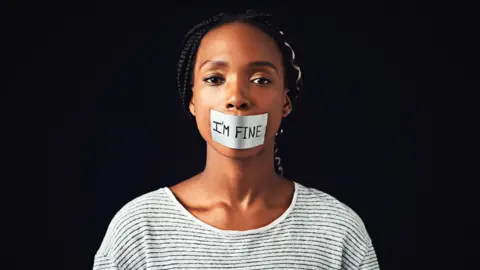 Getty Images Woman with "I'm fine" sticker on her mouth