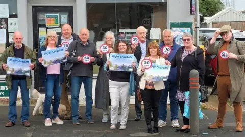 Residents hold 30mph speed limit signs up in protest