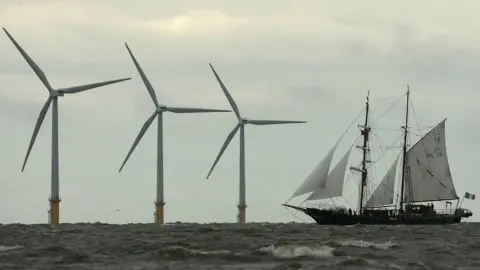 Christopher Furlong Yacht sails past windfarm