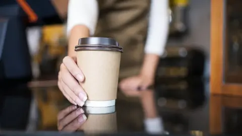 Nitat Termmee/Getty Images Barista holding a coffee cup