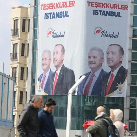 EPA People pass in front of a huge banner with pictures of Turkish President Recep Tayyip Erdogan and Binali Yildirim, candidate of Turkish ruling party Justice and Development Party (AK Party) reading on "Thank you Istanbul" in Istanbul, Turkey, 03 April 2019