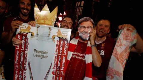 Getty Images Fans holding a replica trophy wearing a Jurgen Klopp mask