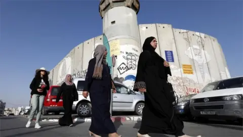 EPA Palestinian women walk past Israeli checkpoint in West Bank (file photo)