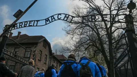 Getty Images Participants seen at the Gate to Auschwitz I with its 'Arbeit macht frei' sign (English: 'work sets you free'), on April 18, 2023