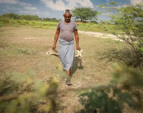 BBC Mr Baisakhu carries animal bones in both hands
