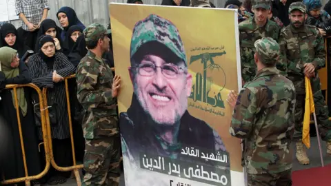 AFP Members of Hezbollah carry a portrait of Mustafa Badreddine at his funeral in Ghobeiry, Beirut (13 May 2016)