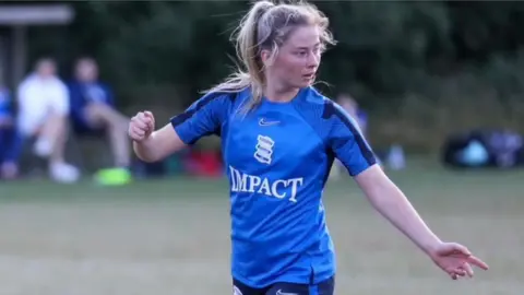 Adam Reapa Charlotte Wilkie wearing blue jersey playing for Birmingham City with her left arm pointing away.