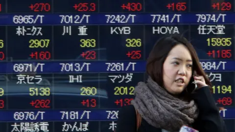 Getty Images A woman passes before a share prices board in Tokyo on January 22, 2016.