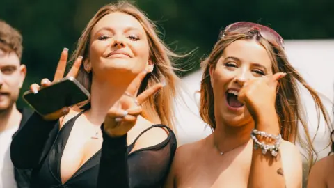 Two women smile and wave at the camera at Love Saves The Day in Bristol