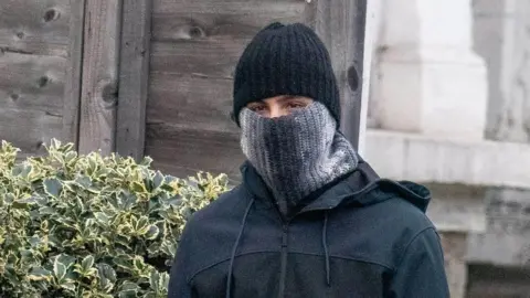 Bradley Page Photo of PC Hussain Chehab wearing a hat and a scarf pulled up over his mouth and nose.