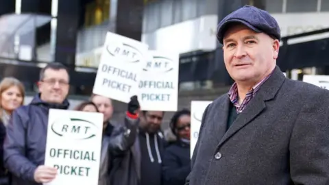 PA Media Mick Lynch stands in front of striking RMT workers