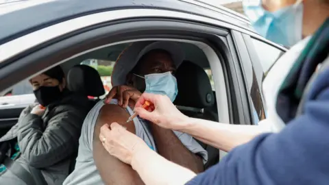 Reuters A man receives a COVID-19 vaccine at a drive-thru vaccination centre in St Albans