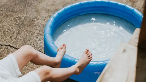 Getty Images A person cooling off in a paddling pool