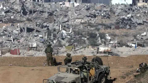 EPA Israeli army soldiers stand guard near the Israel-Gaza border