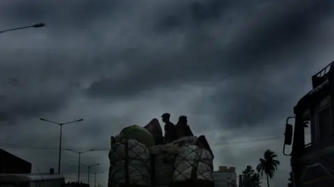 EPA Vegetable vendors travel on a truck with dense clouds are overhead as Cyclone Fani made landfall at neighbouring West Midnapore of West Bengal some 200km west of Kolkata, Eastern India, 03 May 2019