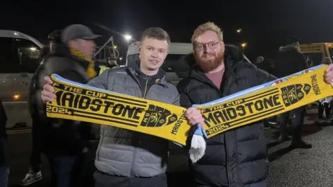 BBC/DANIEL SEXTON Kieran and Will holding their Maidstone scarves