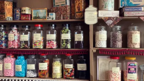 Sweets in jars on shop shelves.