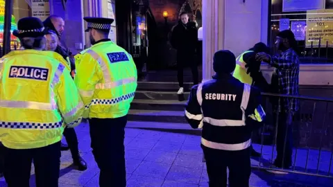 Ollie Conopo/BBC Police officers in yellow hi-viz outside a nightclub