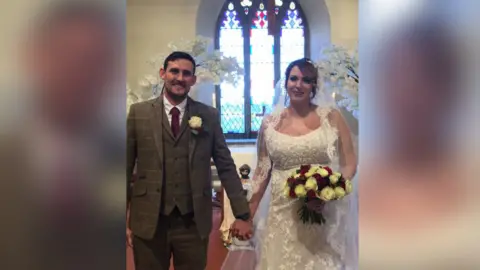 Ben Bainbridge Couple in wedding outfits standing in church